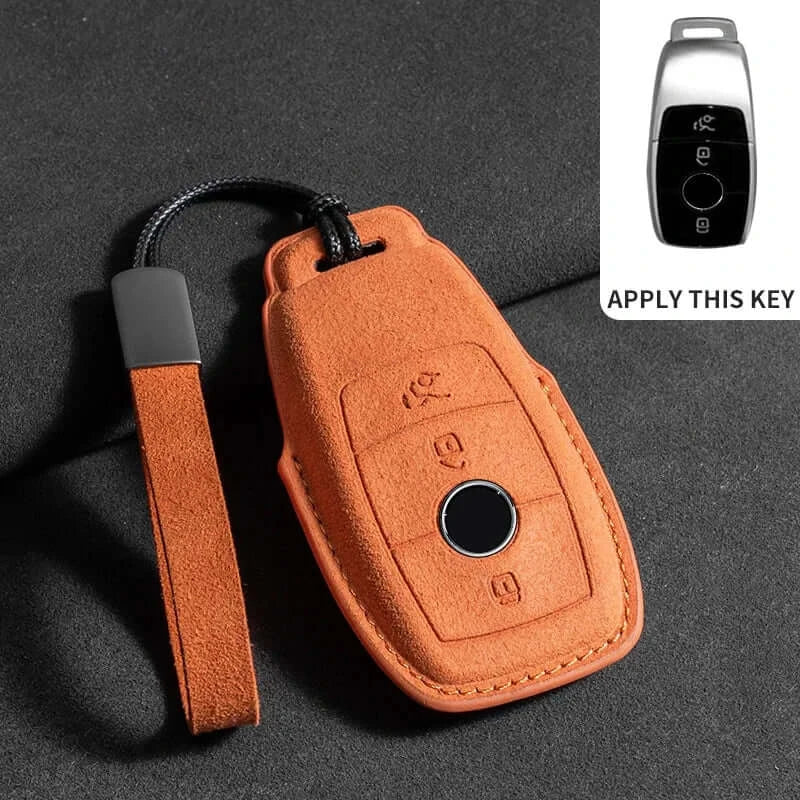 Suede leather key fob case Mercedes Benz in orange with remote buttons and strap on a dark surface.